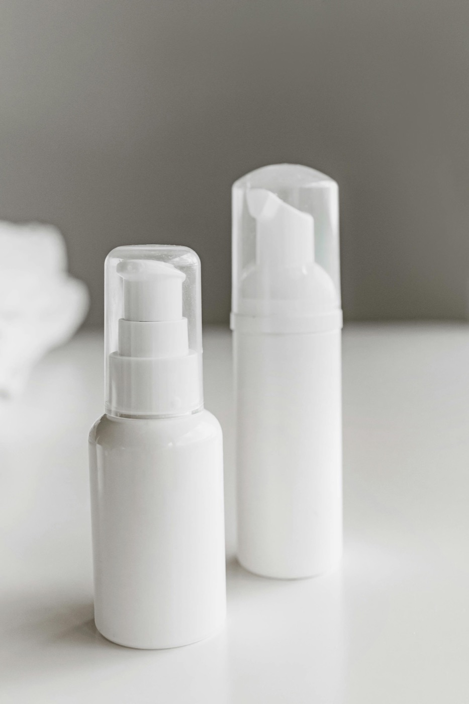 Two facial toner bottles side by side, one labeled alcohol-free and the other showing alcohol denat on its INCI list, on a soft beige background