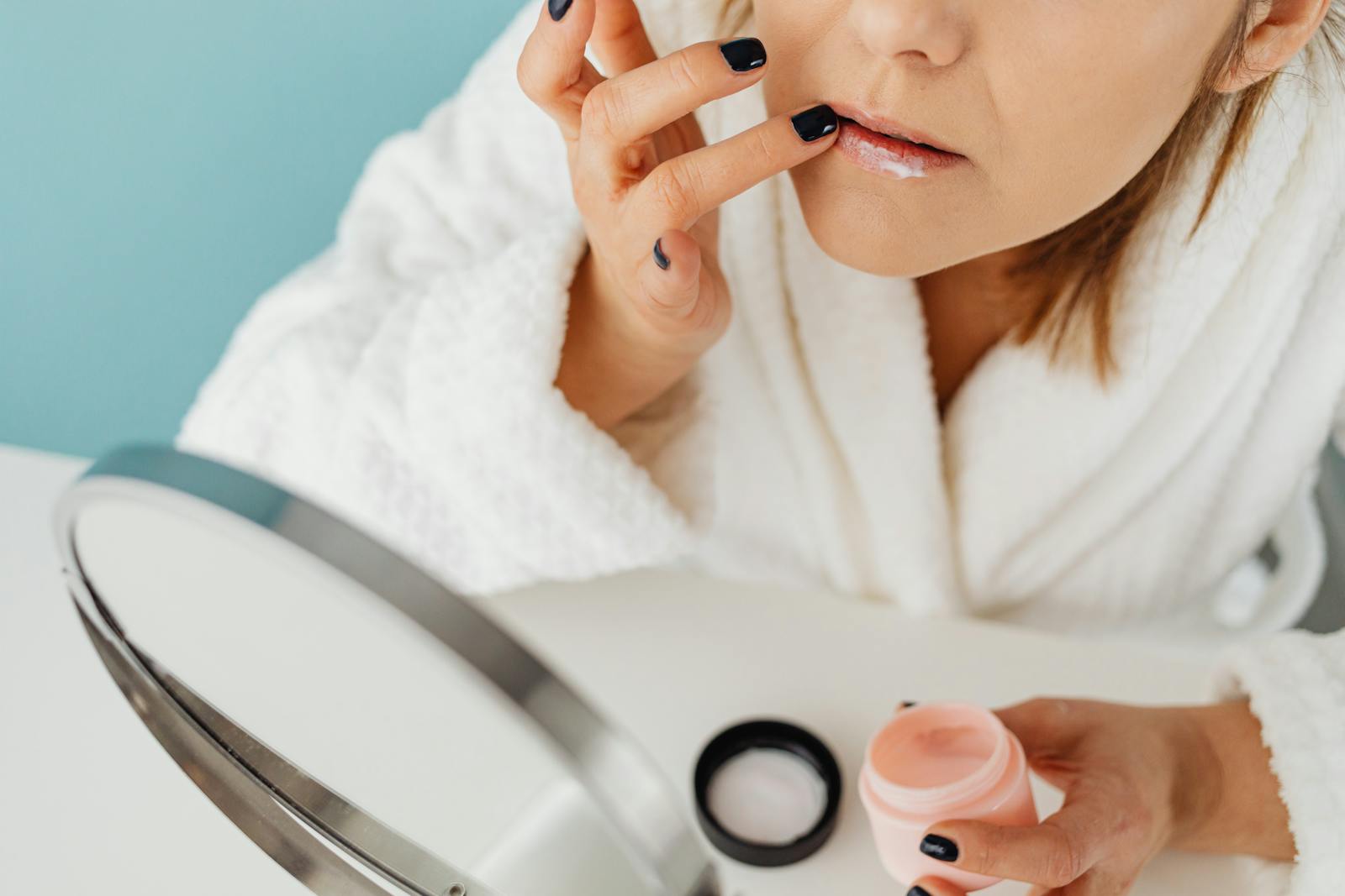 Woman applying azelaic acid multitasker treatment in front of a bathroom mirror