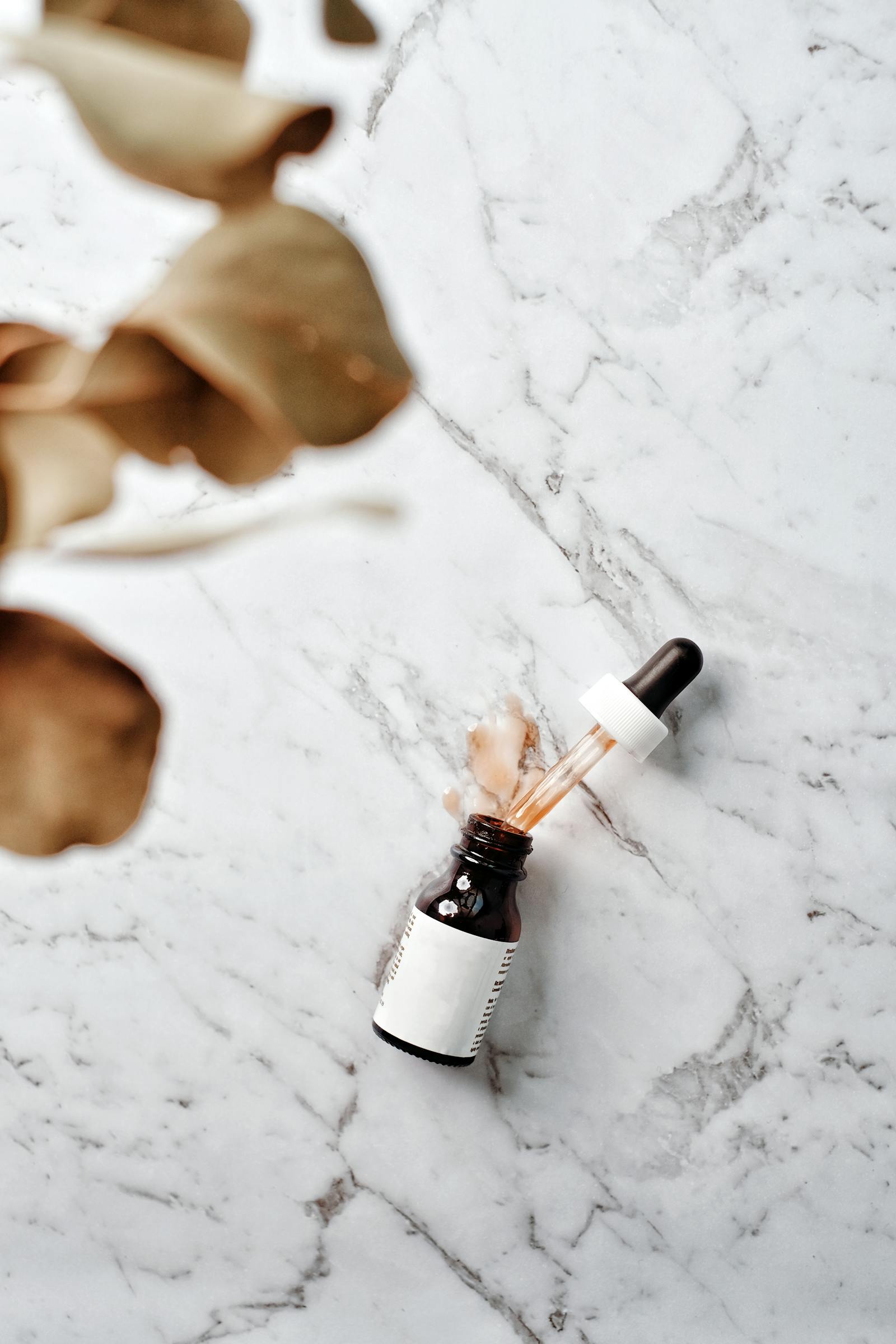 Glass serum bottle with pipette resting on a marble surface, the typical packaging for a high-concentration peptide serum