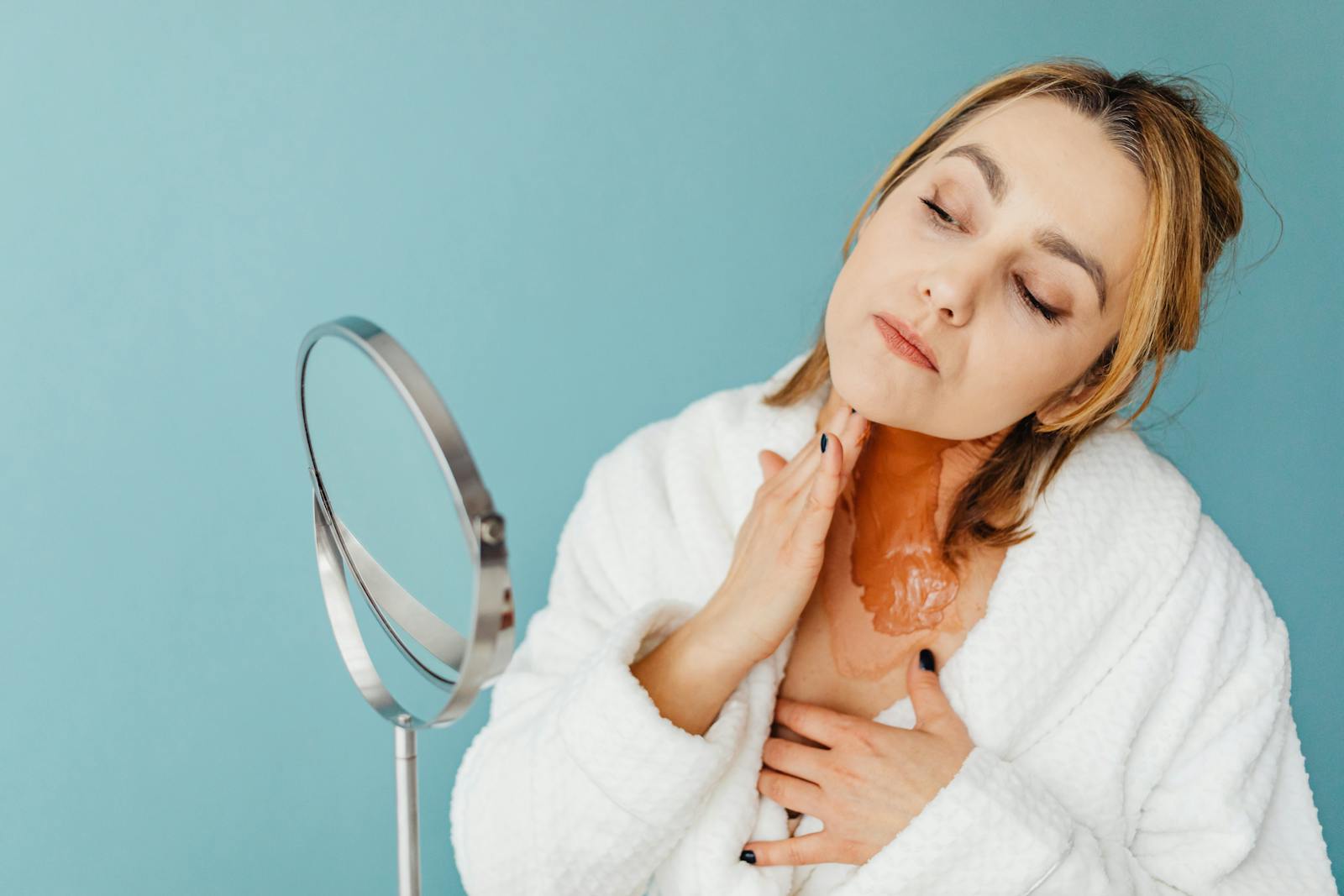 Woman applying retinol treatment as part of her evening skincare routine in front of a mirror