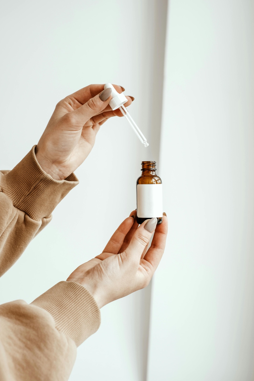 Hand holding a skincare dropper bottle while examining the ingredient label and INCI list